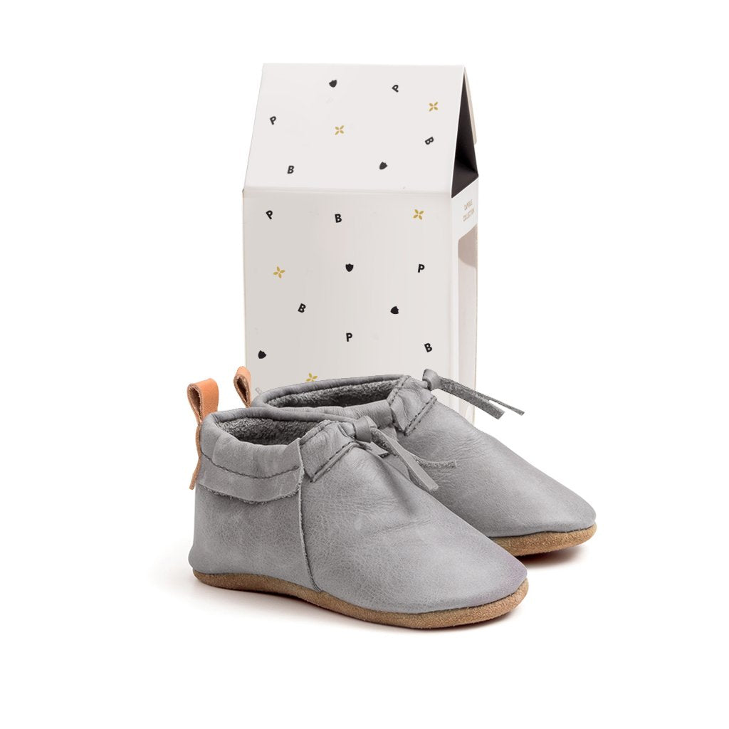 Pair of boots in colour grey next to box